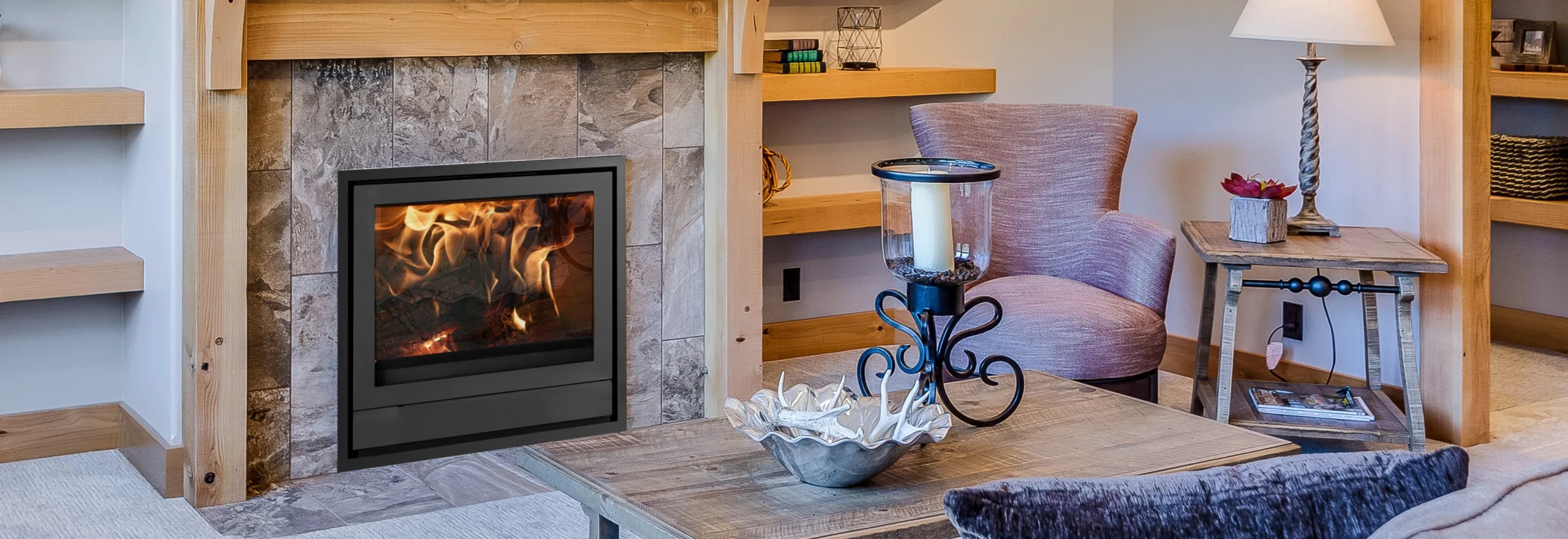 Modern&aacute; ob&yacute;vačka s krbovou vložkou NIQ 43 Nestor Martin zabudovanou v stene, s veľkou zasklenou plochou a v&yacute;razn&yacute;m plameňom v ohnisku.